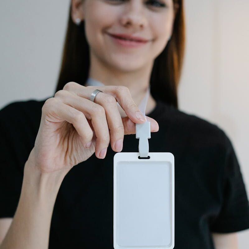 Portrait d'une femme joyeuse tenant un badge d'identification vierge, parfait pour la promotion d'une entreprise ou d'un événement.